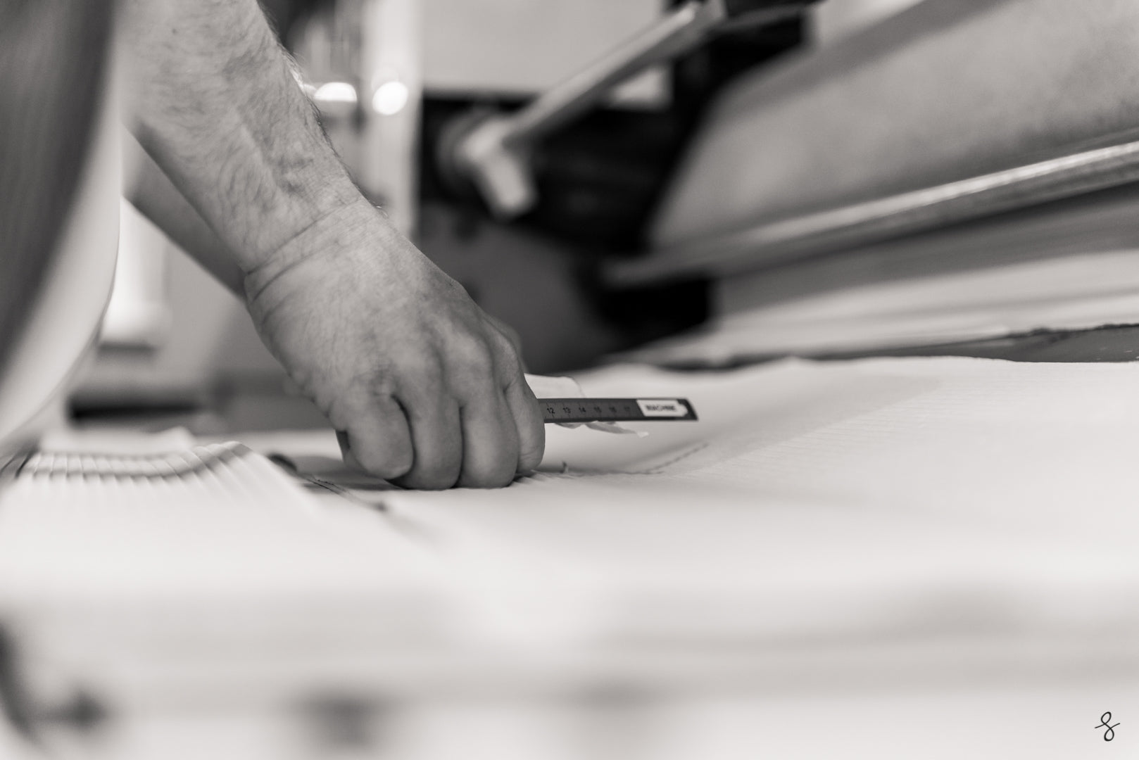 Main d'un artisan ajustant un tissu blanc avec précision dans un atelier de plissage en Bretagne, illustrant le savoir-faire artisanal des chemises plissées de Bourrienne Paris X.