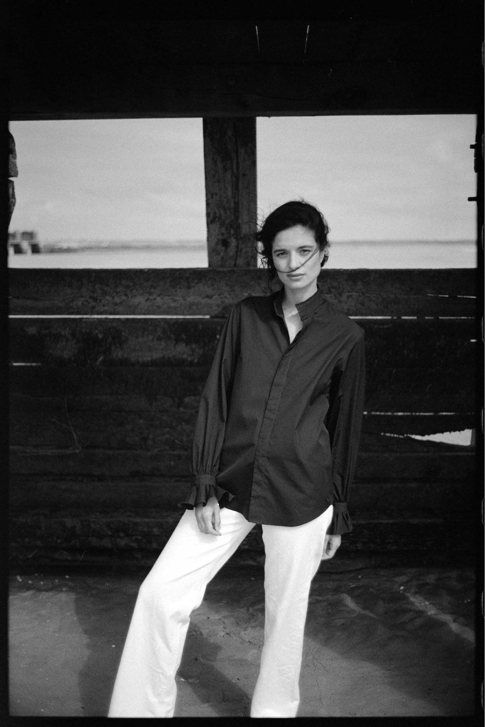 BOURRIENNE PARIS X: Photo vue de face, le mannequin se tient debout, la photo est en noir et blanc, la chemise en conçue en popeline bleu marine.