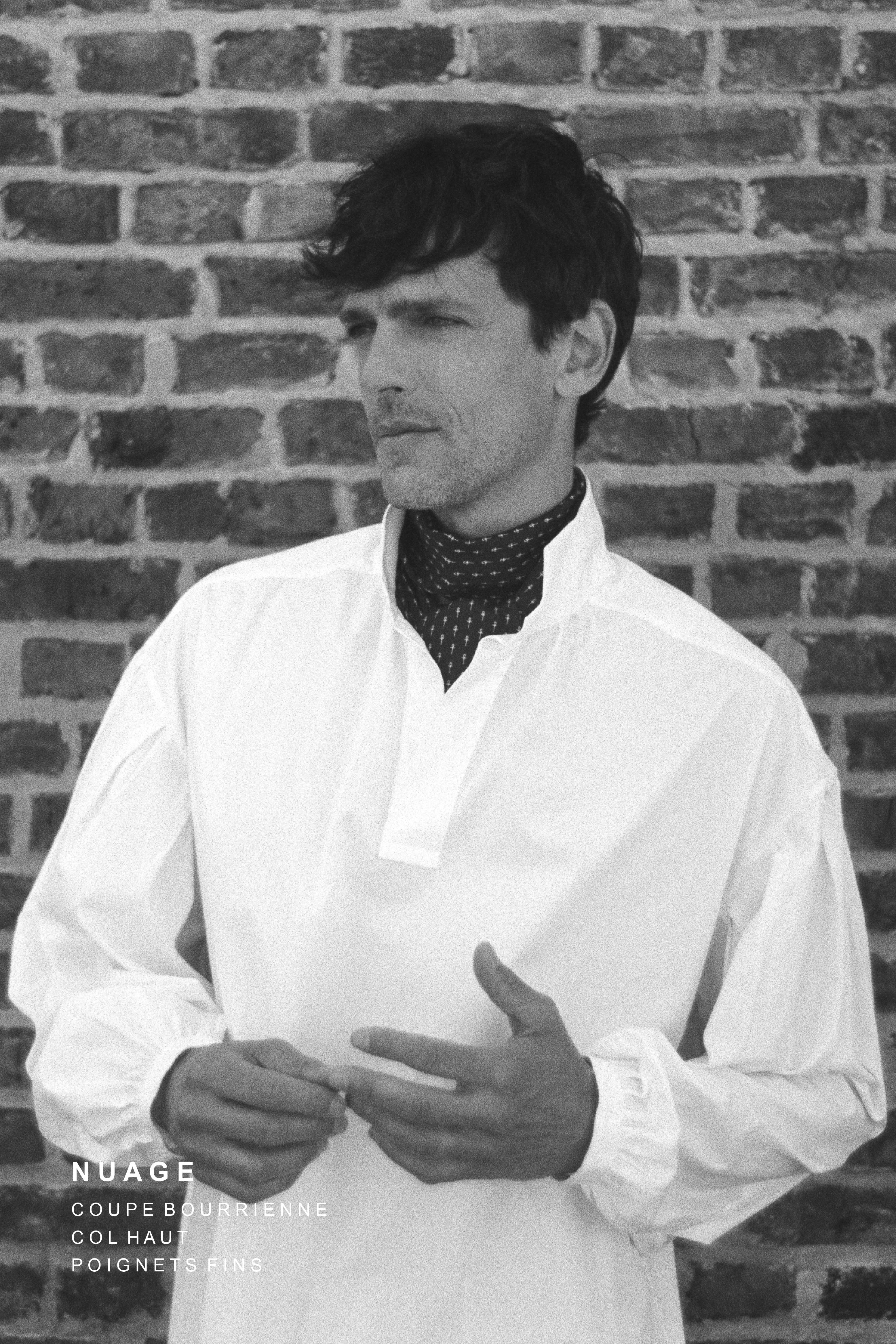 BOURRIENNE PARIS X: Photo prise de face, le mannequin porte une chemise en popeline blanche avec de grandes manches napoléoniennes, un col haut et des poignets fins et resserrés. La photo est en noir et blanc et est un modèle ample, vaporeux et qui taille grand.