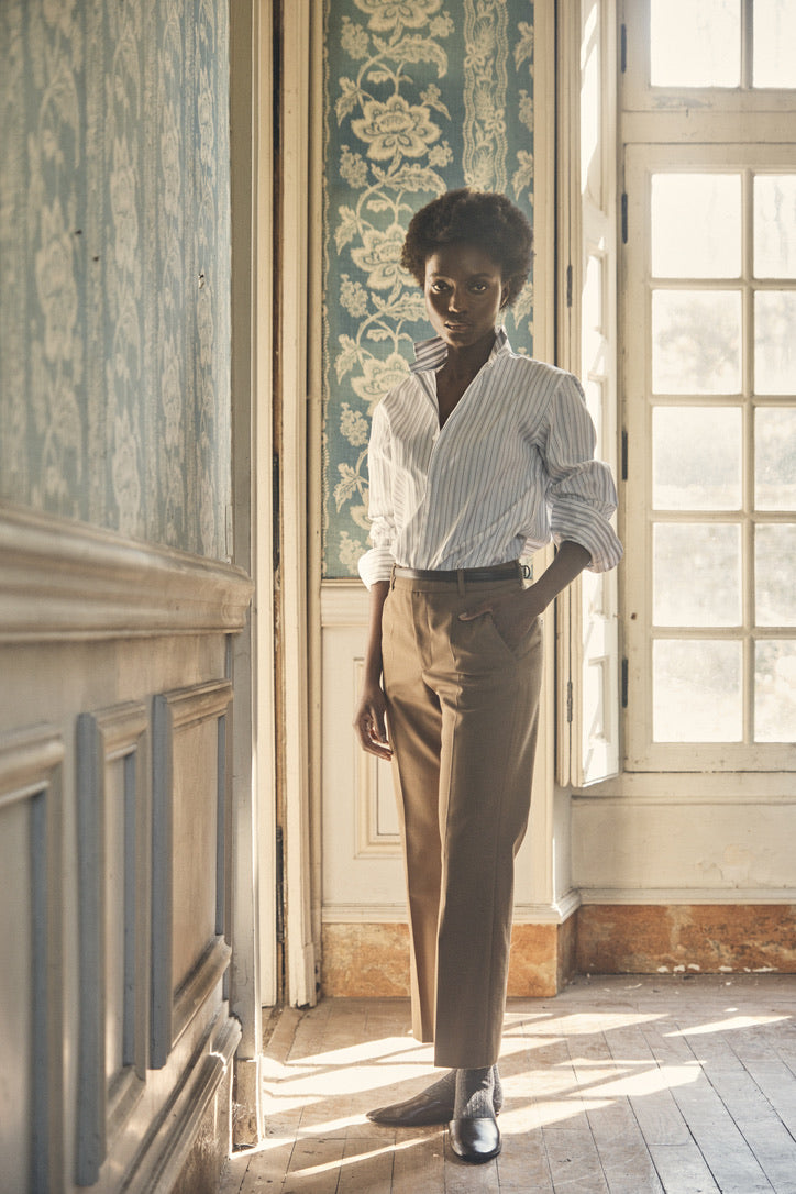 Chemise AMAZONE Rayée Kaki portée par une mannequin dans une maison avec des tapisseries anciennes.