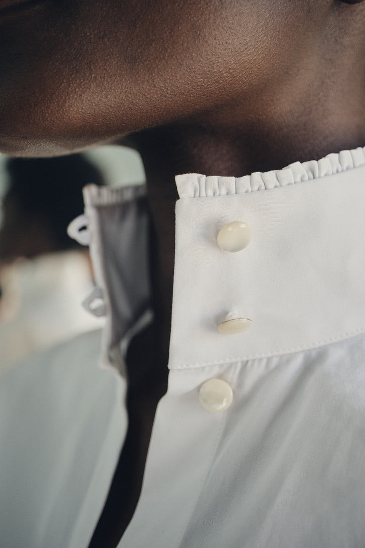 Close-up sur le cou de la mannequin portant la chemise PRÉCIEUSE, col ouvert avec trois boutons ronds en nacre.