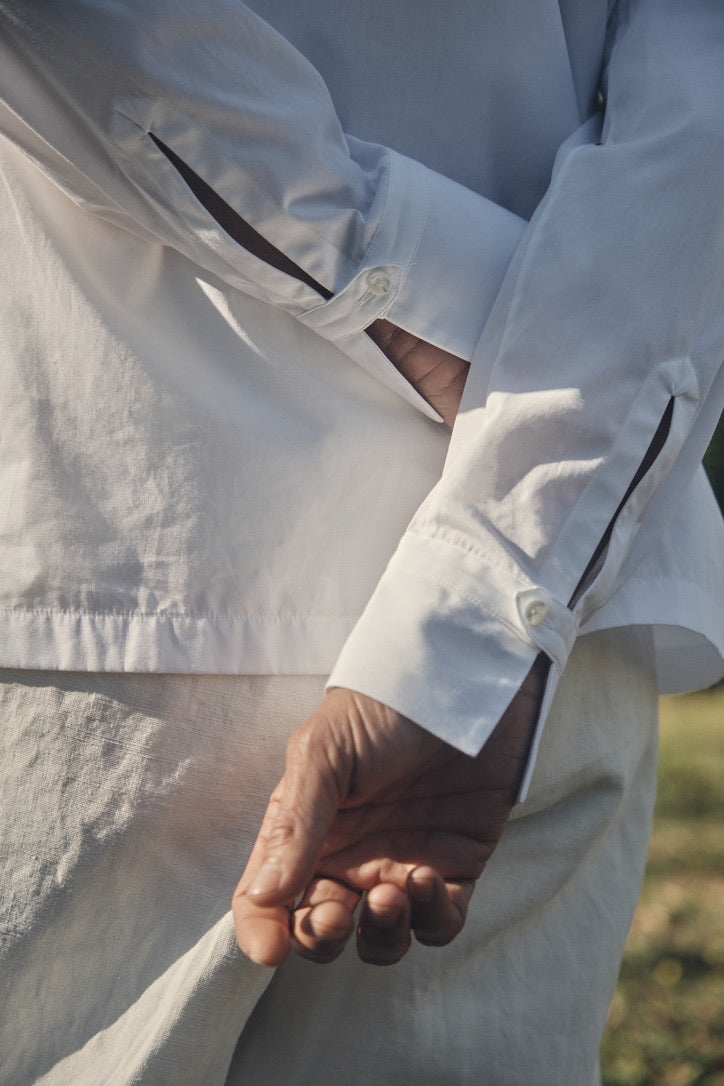 Photo gros plan d'un homme les mains croisés dans le dos portant une chemise nommé VOYAGE, elle est en 100% Coton, fabriqué en Europe, une coupe Bourrienne, un col Français et des poignets Bourrienne.
