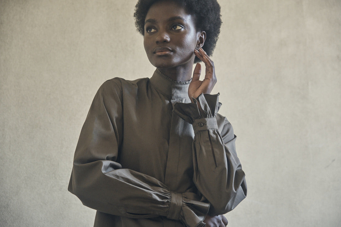 Femme portant la chemise BOUDOIR Kaki, prise en contre-plongée.