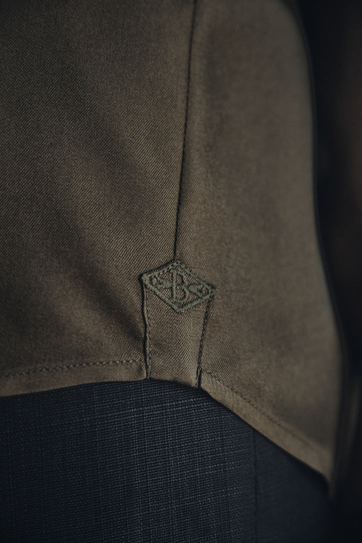 Close-up sur le logo brodé Bourrienne Paris X sur le côté de la chemise COMTESSE Soie Kaki.