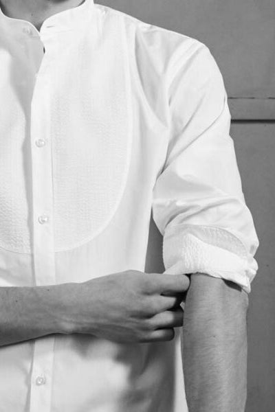 Close-up sur la manche de la chemise blanche à plastron rond.
