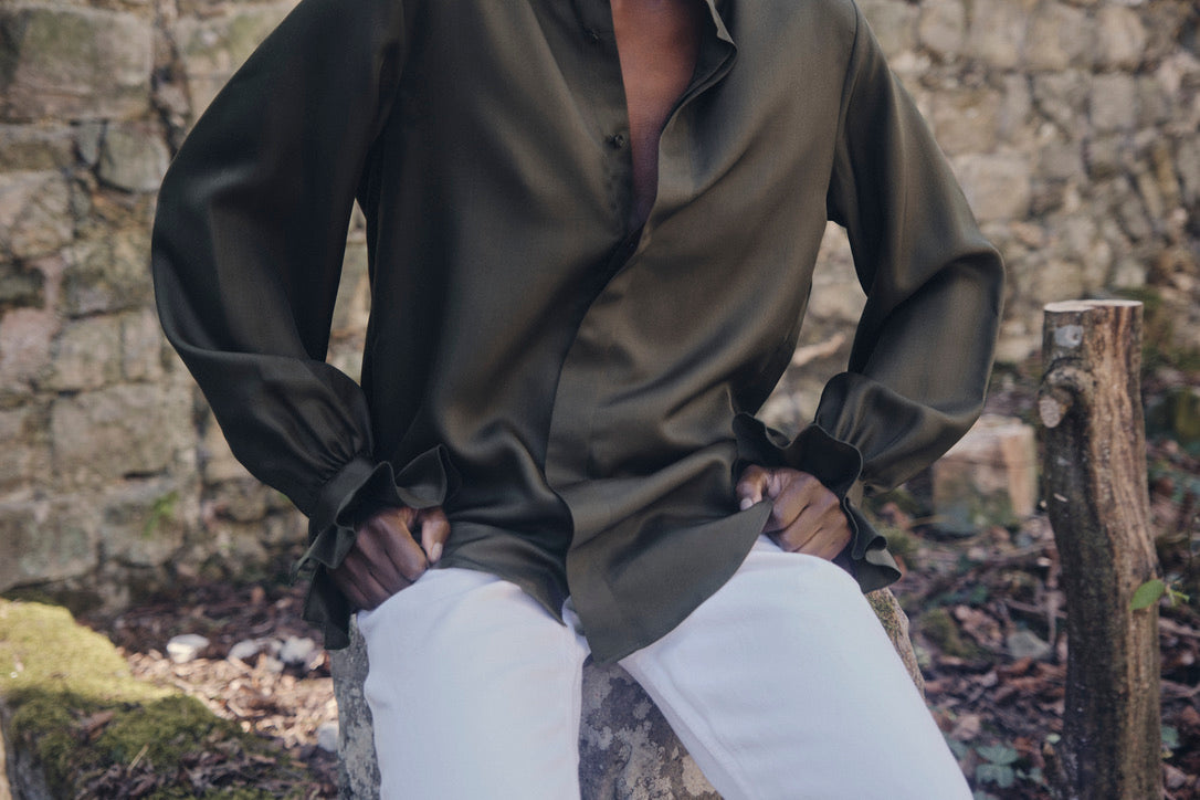 Close-up sur la fluidité du tissu de la chemise BOUDOIR Soie Kaki portée par une mannequin assise.