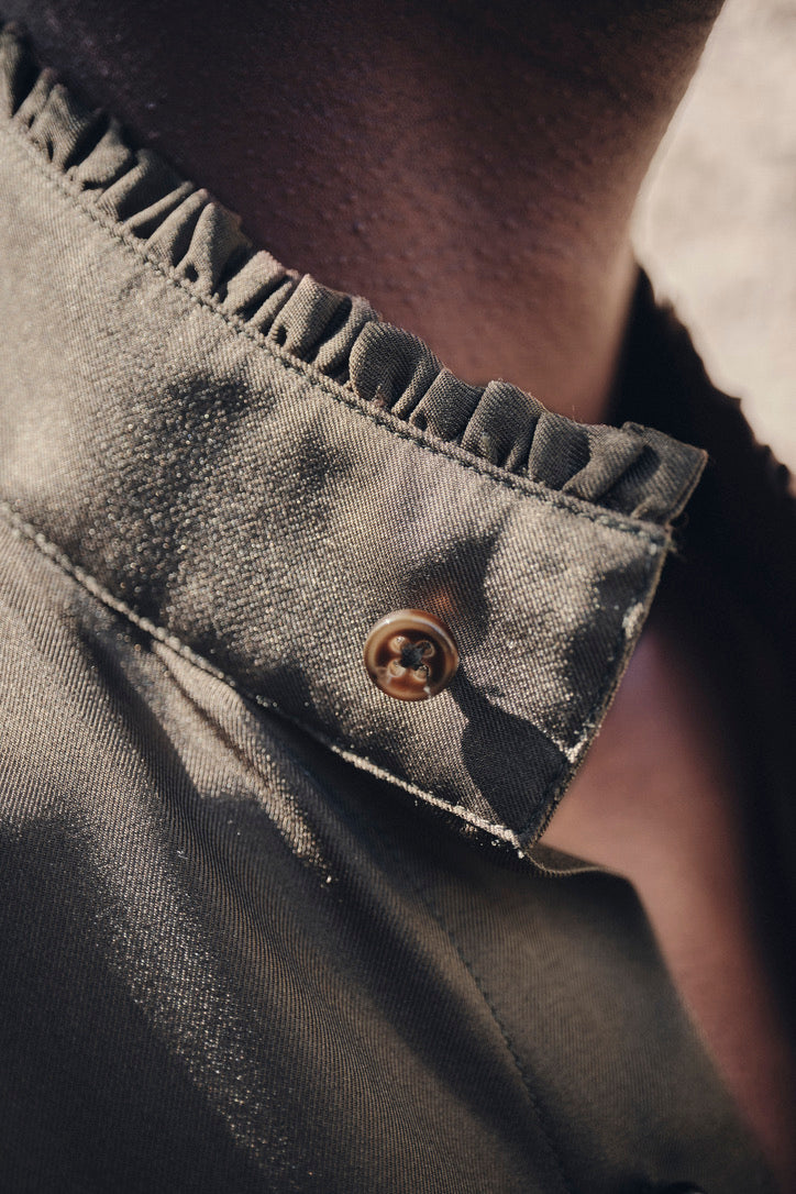 Close-up sur le col orné de petits volants de la chemise BOUDOIR Soie Kaki portée par une mannequin.