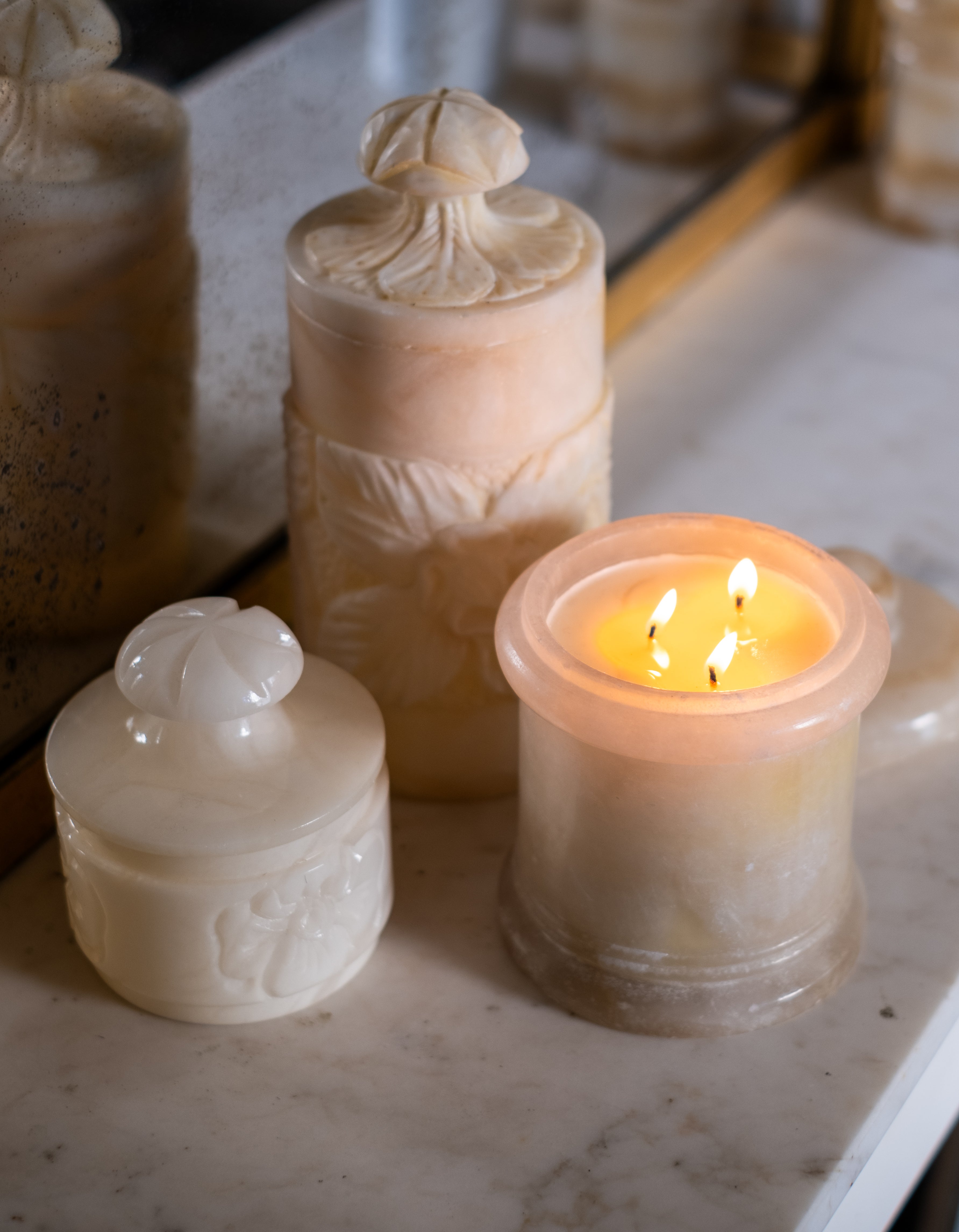 3 bougies en pot en albatre, dont une allumée (à 3 mèches).