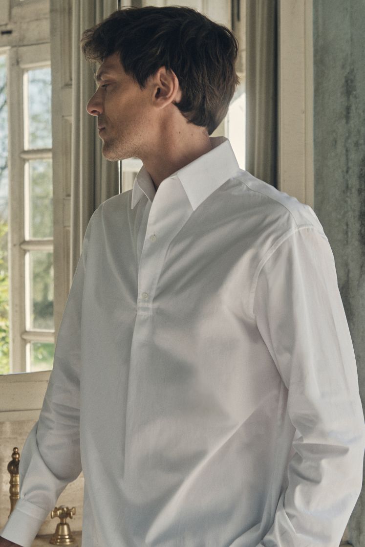 Une photo plan poitrine d'un homme qui regarde de profil, il. porte une chemise 100% Coton, fabriqué en Europe, une coupe Bourrienne, un col Français et des Poignets Bourrienne.