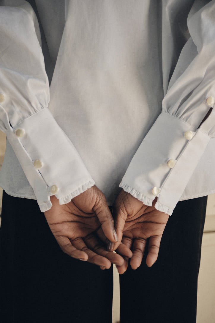 Close-up sur les poignets longs de la chemise PRÉCIEUSE, avec quatre boutons en nacre de chaque côté.