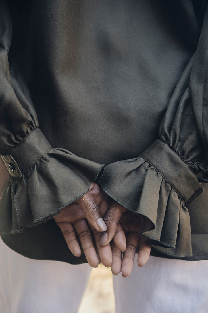 Close-up sur les poignets à volants de la chemise.