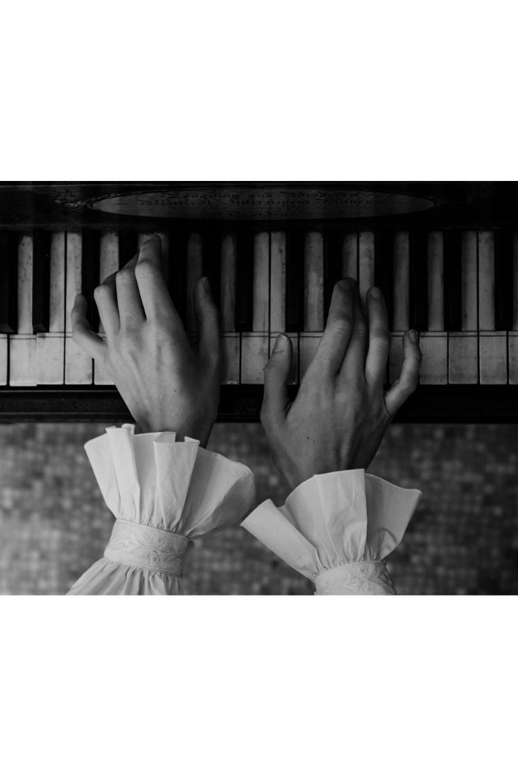 Mains jouant du piano portant la chemise BOUDOIR avec ses poignets à volants.