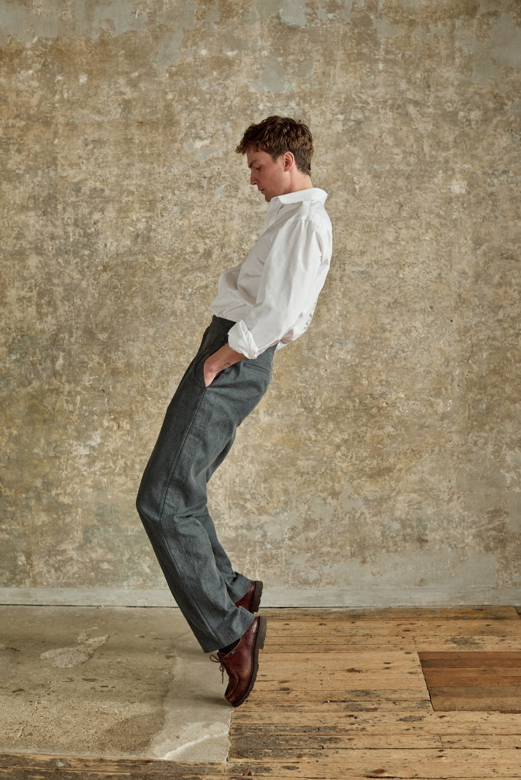 Homme portant le pantalon HORIZON gris, de profil, avec une chemise blanche.
