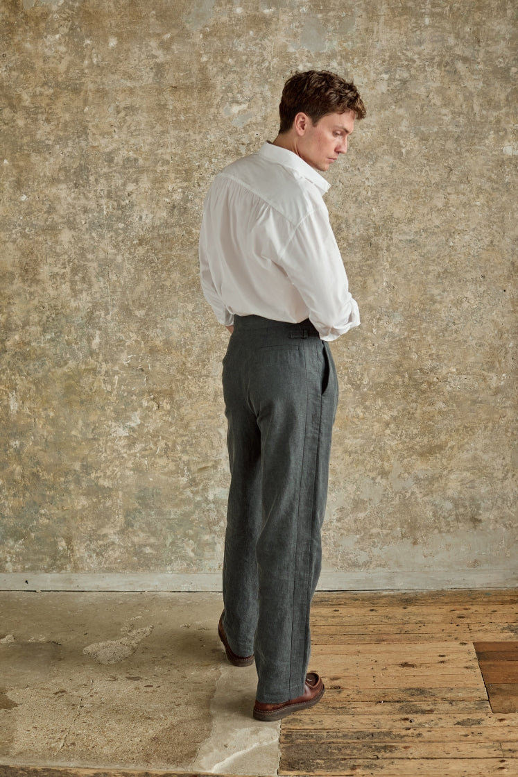 Homme portant le pantalon HORIZON gris, de dos, avec une chemise blanche.