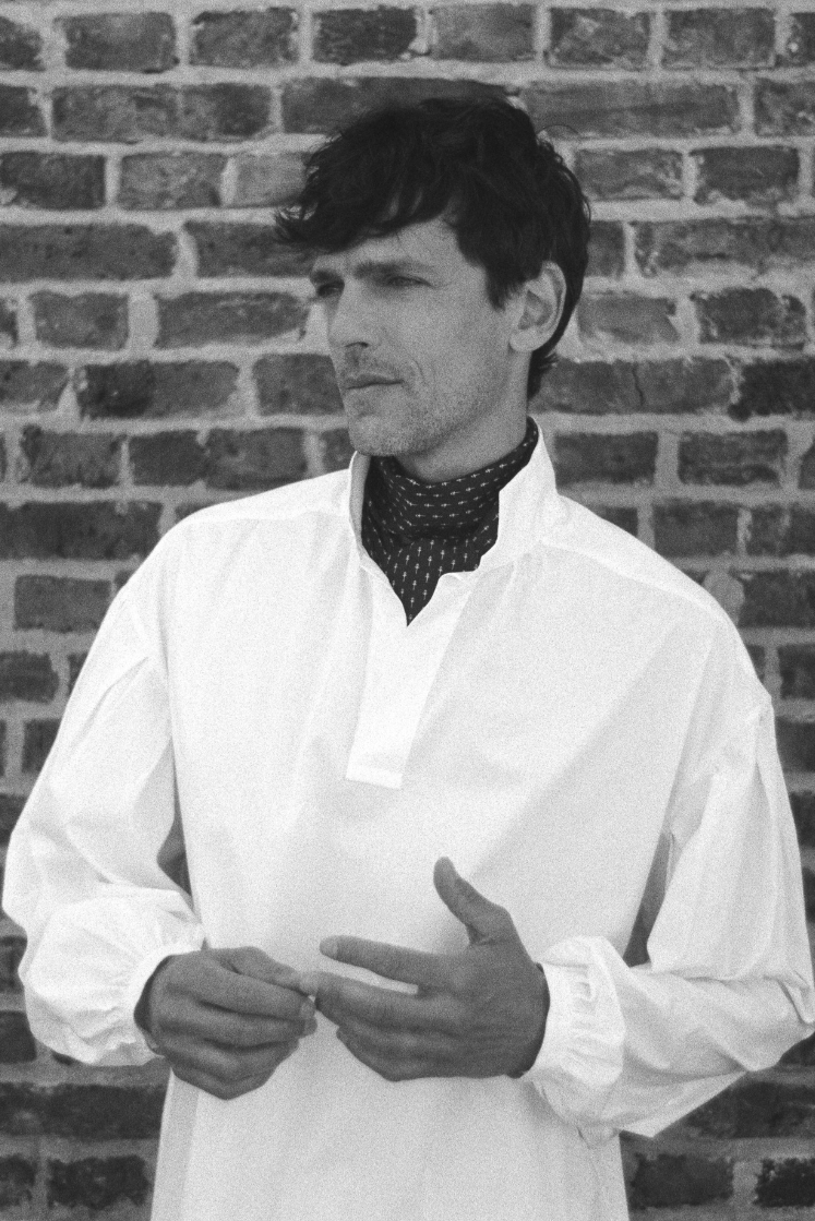 BOURRIENNE PARIS X: Photo prise de face, le mannequin porte une chemise en popeline blanche avec de grandes manches napoléoniennes, un col haut et des poignets fins et resserrés. La photo est en noir et blanc et est un modèle ample, vaporeux et qui taille grand.