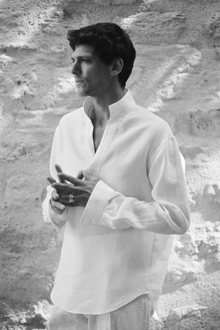 Photo en noir et blanc d'un homme portant la chemise sculpteur en lin blanc, avec un col haut.