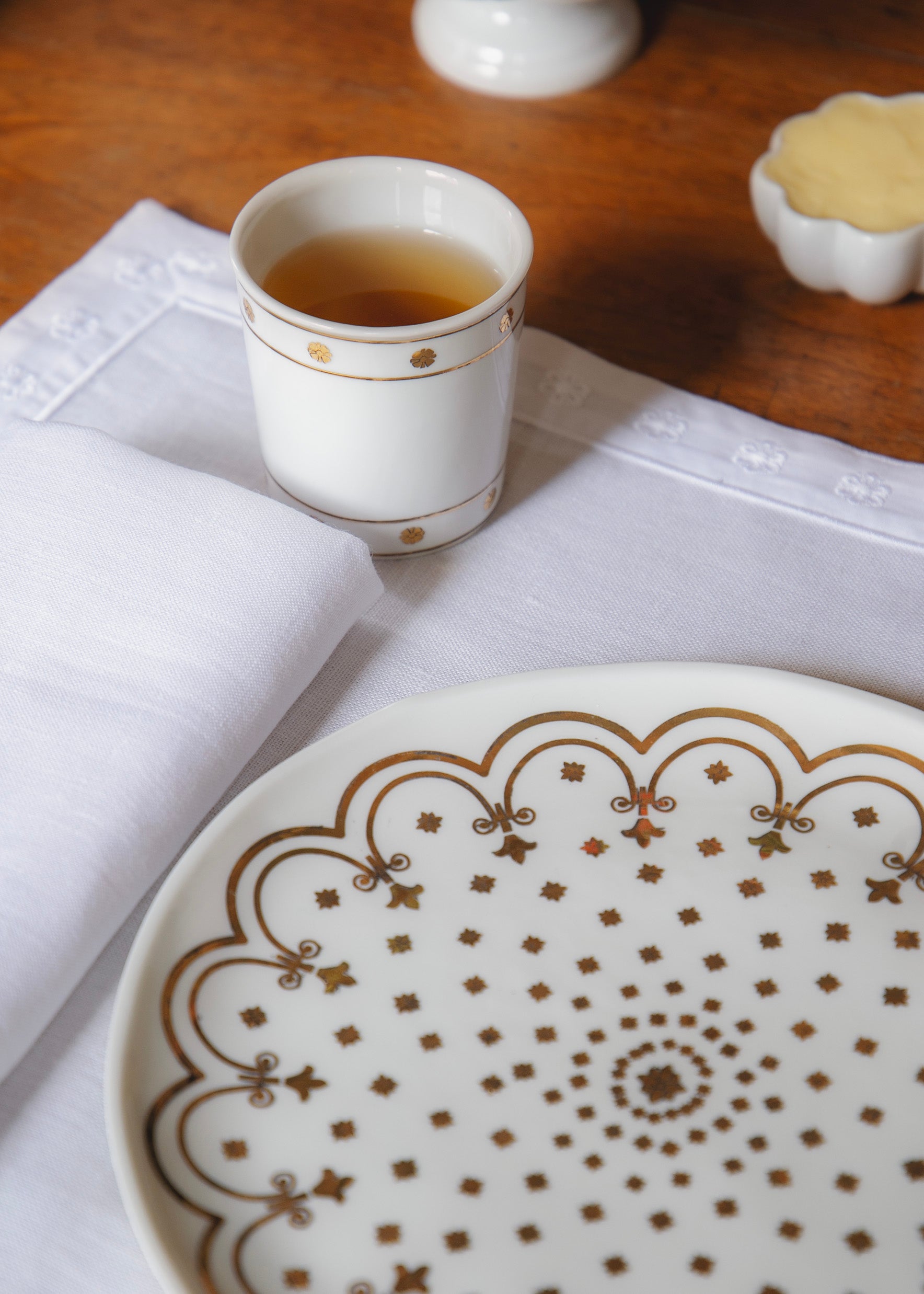 Assiette en porcelaine issue de la collaboration Bourrienne Paris X et Alix D. Reynis posée sur le set de table avec la timbale issue de la même collaboration