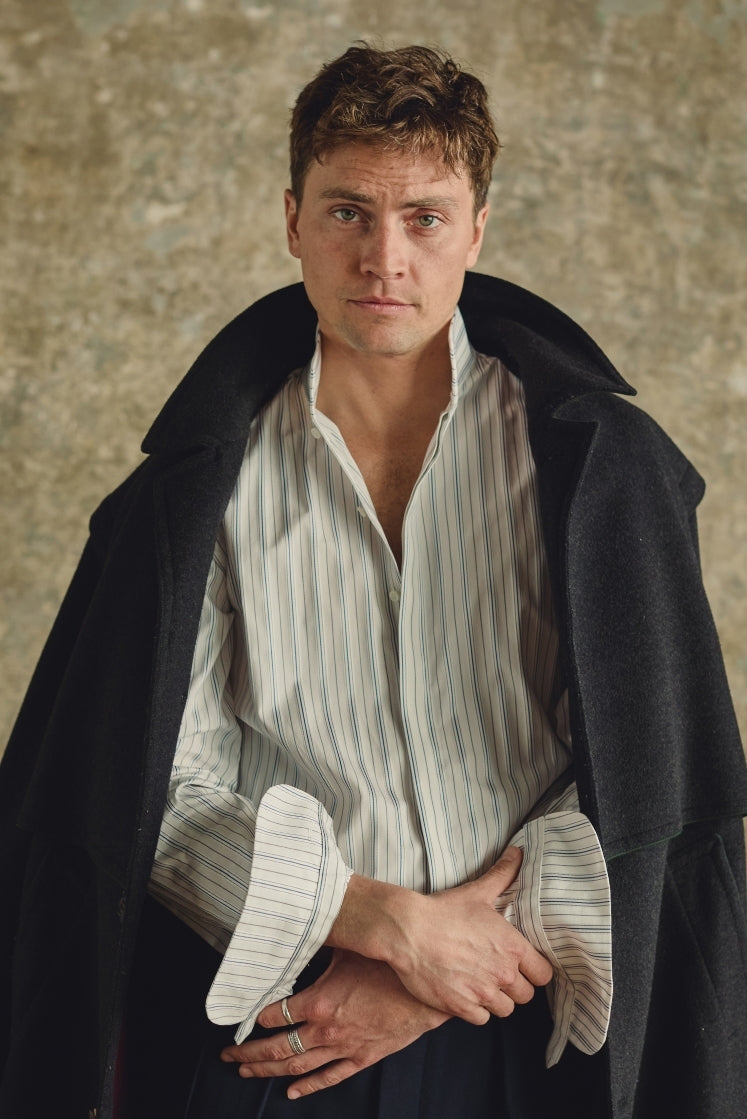 Chemise homme APPARAT rayée bleu et gris en coton avec col haut et poignets Bourrienne, portée avec un manteau d'h. ver oversize noir.