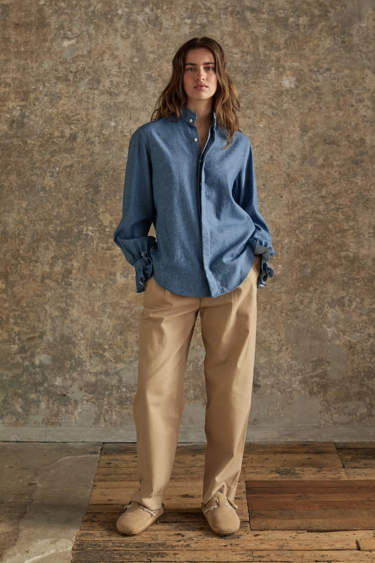 Femme portant la chemise Boudoir en denim bleu ciel, plan plein pied avec pantalon beige, look intemporel Bourrienne