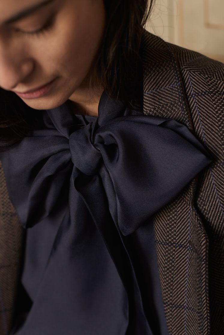 Close-up sur le col lavallière de la chemise COMTESSE en soie navy, attaché en noeud papillon.