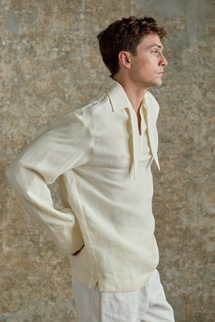 Homme portant la chemise blanche DOCK en lin et laine, col français à foulard intégré inspiré des vareuses, plan américain vue de profil.