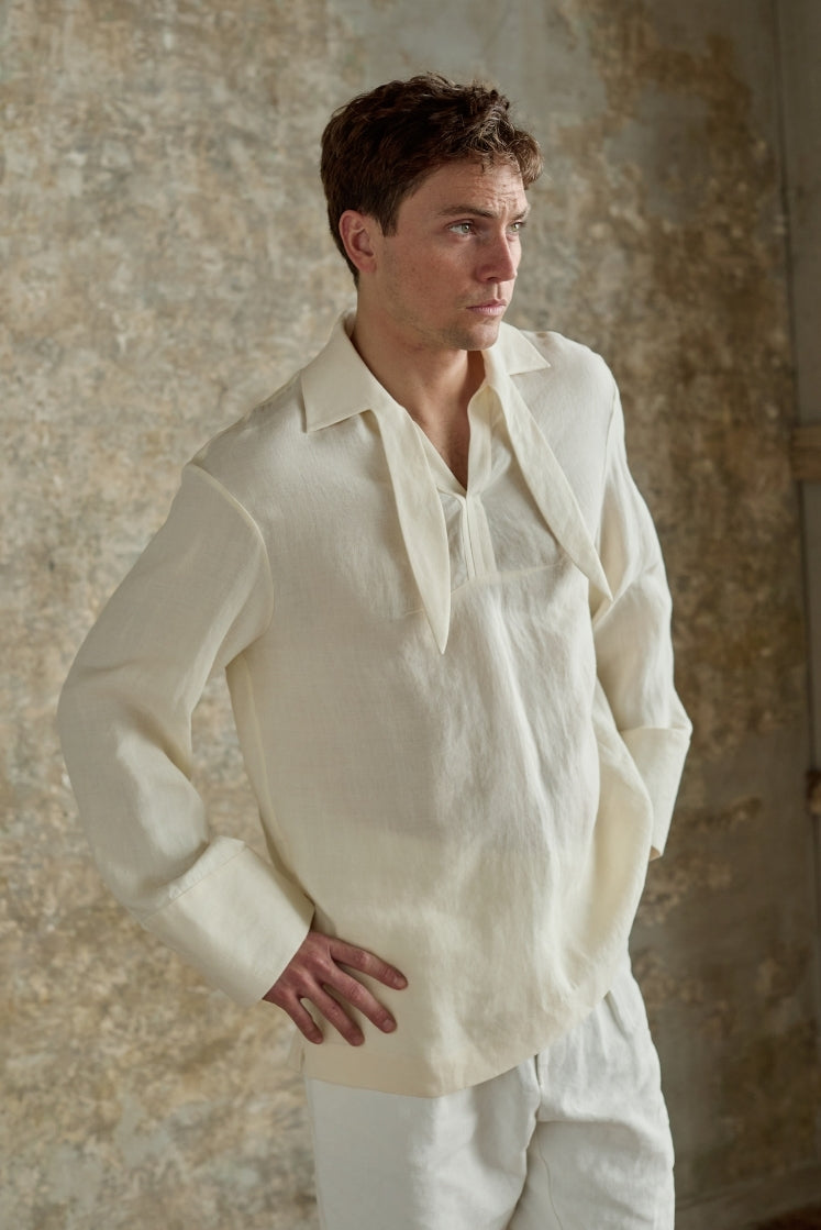 Homme portant la chemise blanche DOCK en lin et laine, col français à foulard intégré inspiré des vareuses, poignets larges, plan américain vue de trois quarts.