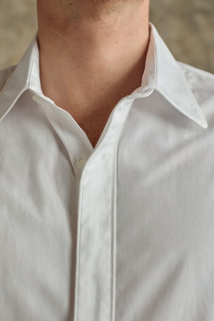 Homme portant la chemise blanche GALERIE en popeline de coton italienne, closeup sur le col français légèrement déboutonné, vue de face.