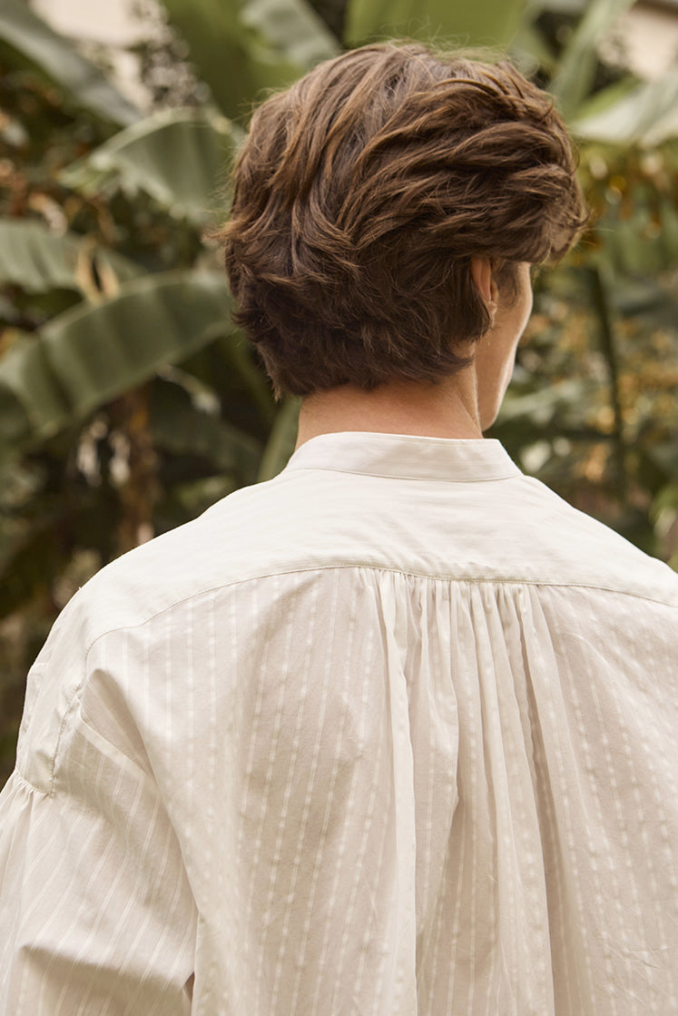 Closeup sur le dos de la chemise blanche à rayures blanches avec ses délicates fronces créant du volume