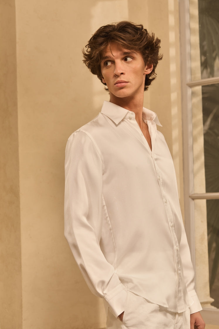 Homme portant une chemise en soie blanche avec un col français et un pantalon en lin blanc.