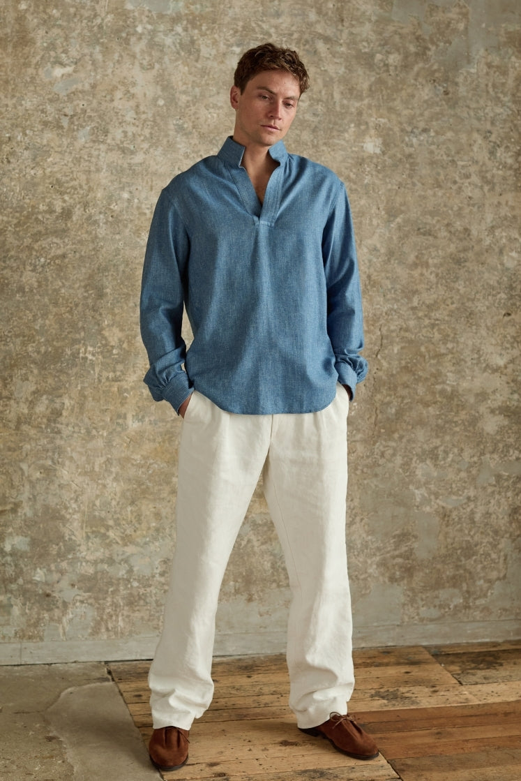 Homme portant la chemise SCULPTEUR en denim bleu clair, col haut, mains dans les poches.