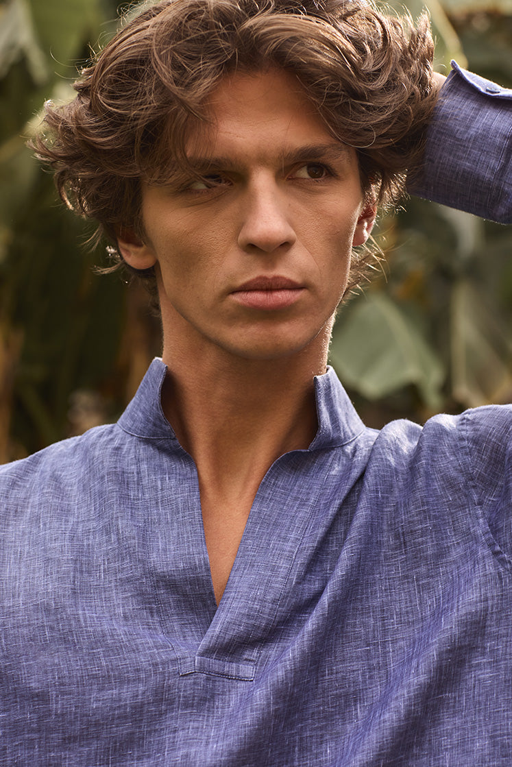 Plan épaule d'un homme portant la chemise SCULPTEUR en lin bleu navy à col haut, passant la main dans ses cheveux.