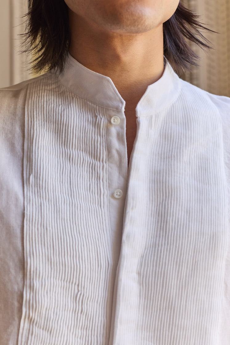 Homme portant la chemise blanche COMÉDIEN en lin avec un plastron plissé à la main en Bretagne.