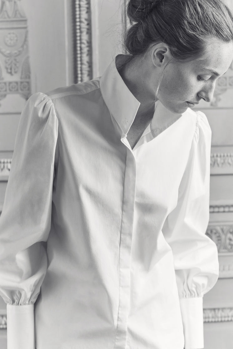 Femme portant la chemise blanche CROISIÈRE à col haut et poignets longs.