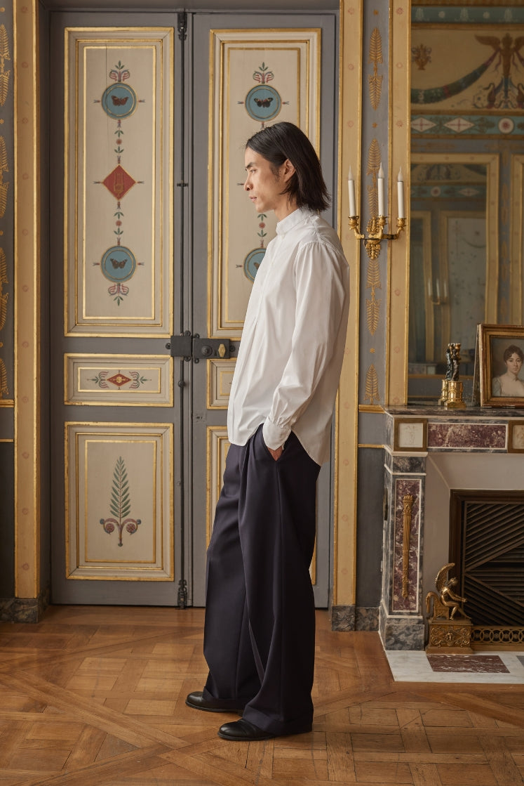 Homme portant la chemise ÉPICURIEN blanche de profil avec un pantalon noir.
