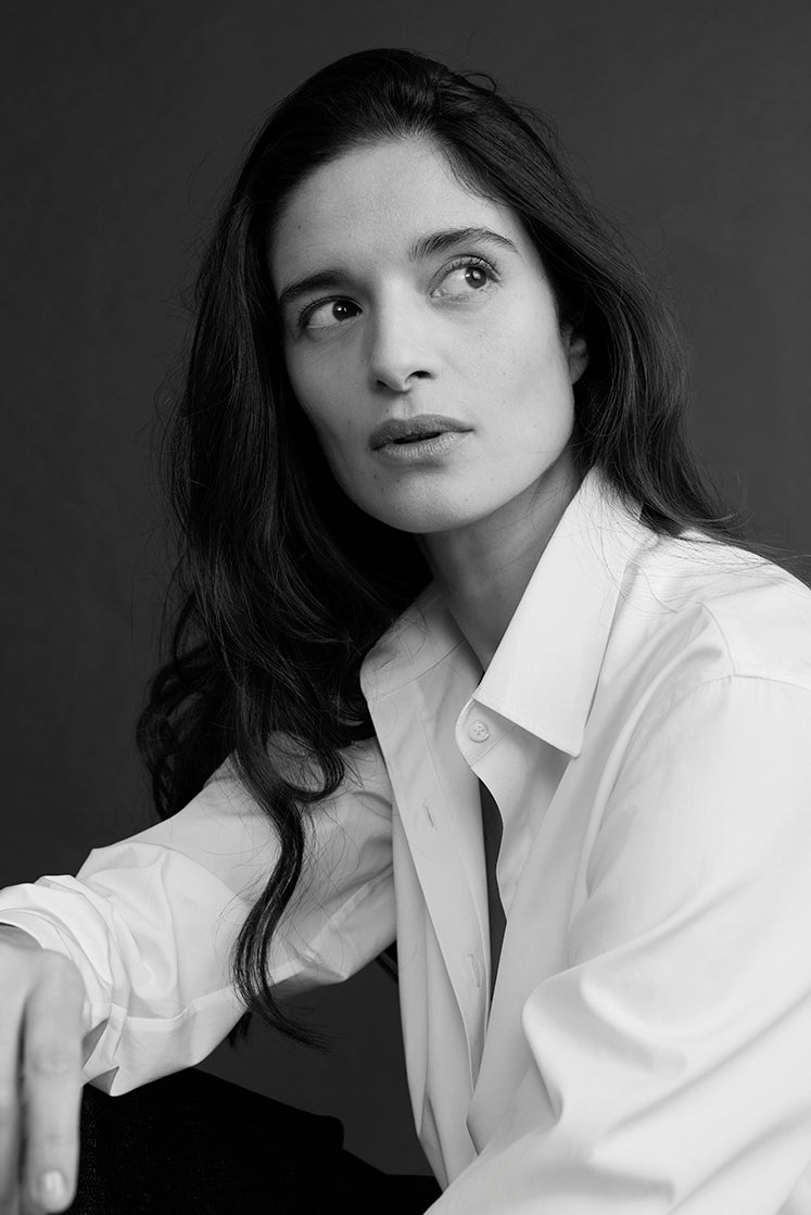 Portrait noir et blanc d’une femme en chemise blanche légèrement ouverte à col français.