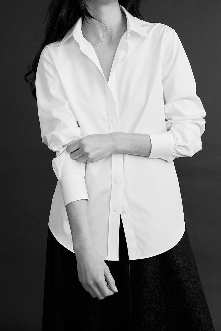Femme portant une chemise blanche intemporelle, manches retroussées.