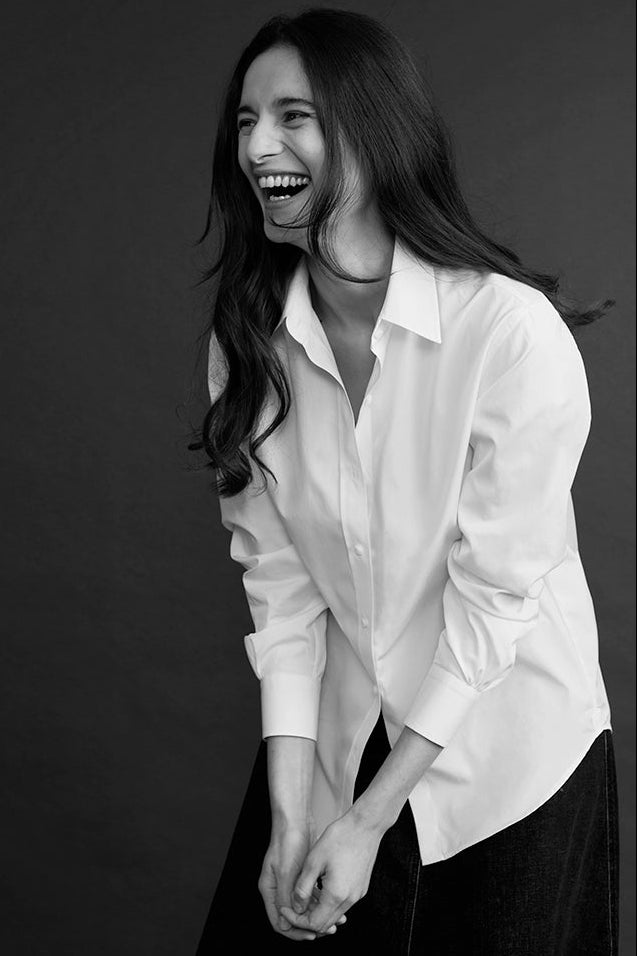 Femme riant, portant une chemise blanche intemporelle à col français.