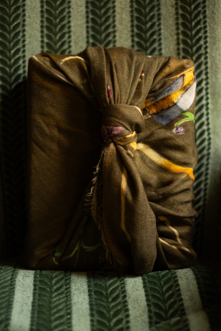 Écharpe Fortunée en cachemire kaki aux motifs de l'Hôtel de Bourrienne enveloppée autour d'une boite.