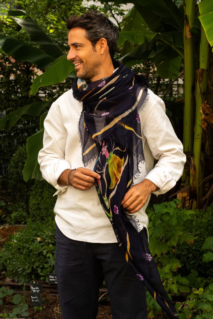 Homme portant l'écharpe Fortunée en cachemire navy aux motifs de l'Hôtel de Bourrienne, enroulée autour de son cou sur une chemise blanche.