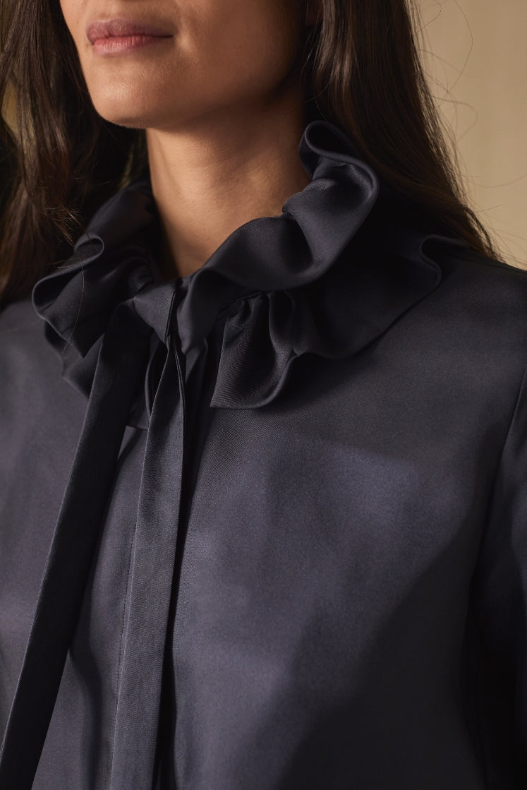 close-up sur le col à volants noué de la chemise PASTEL en soie navy.