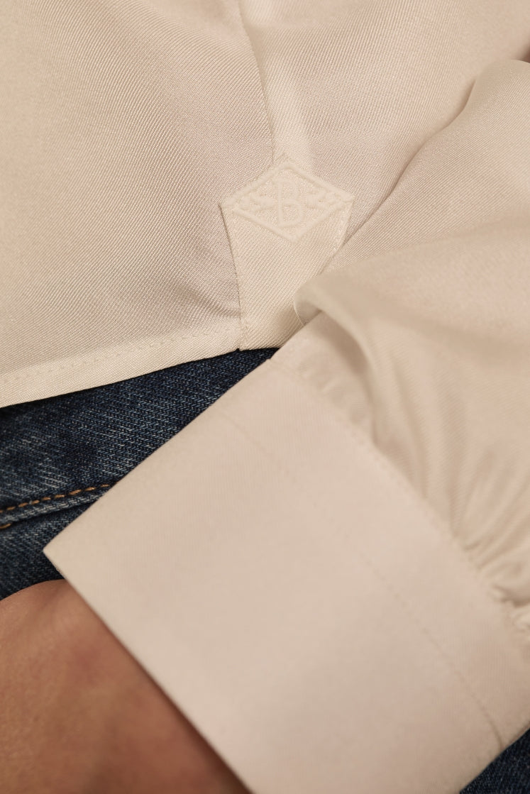 close-up de l'hirondelle brodée du logo Bourrienne Paris X sur le côté de la chemise PASTEL en soie blanche.