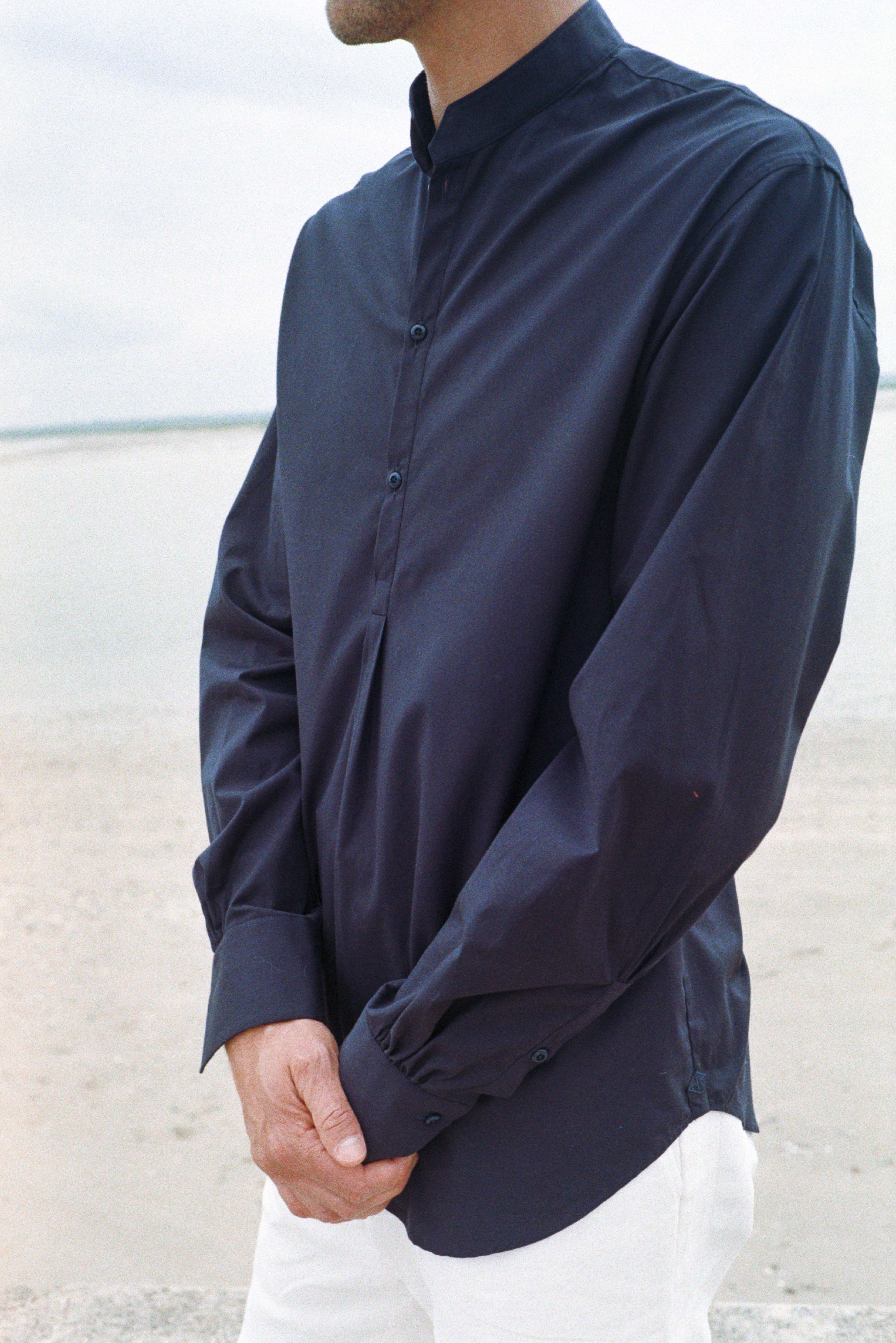 BOURRIENNE PARIS X: Photo prise de face, close up sur le devant de la chemise en popeline bleu marine, on aperçoit les détails du col officier biseauté ainsi que de la patte de boutonnage qui s’arrête à la taille. 