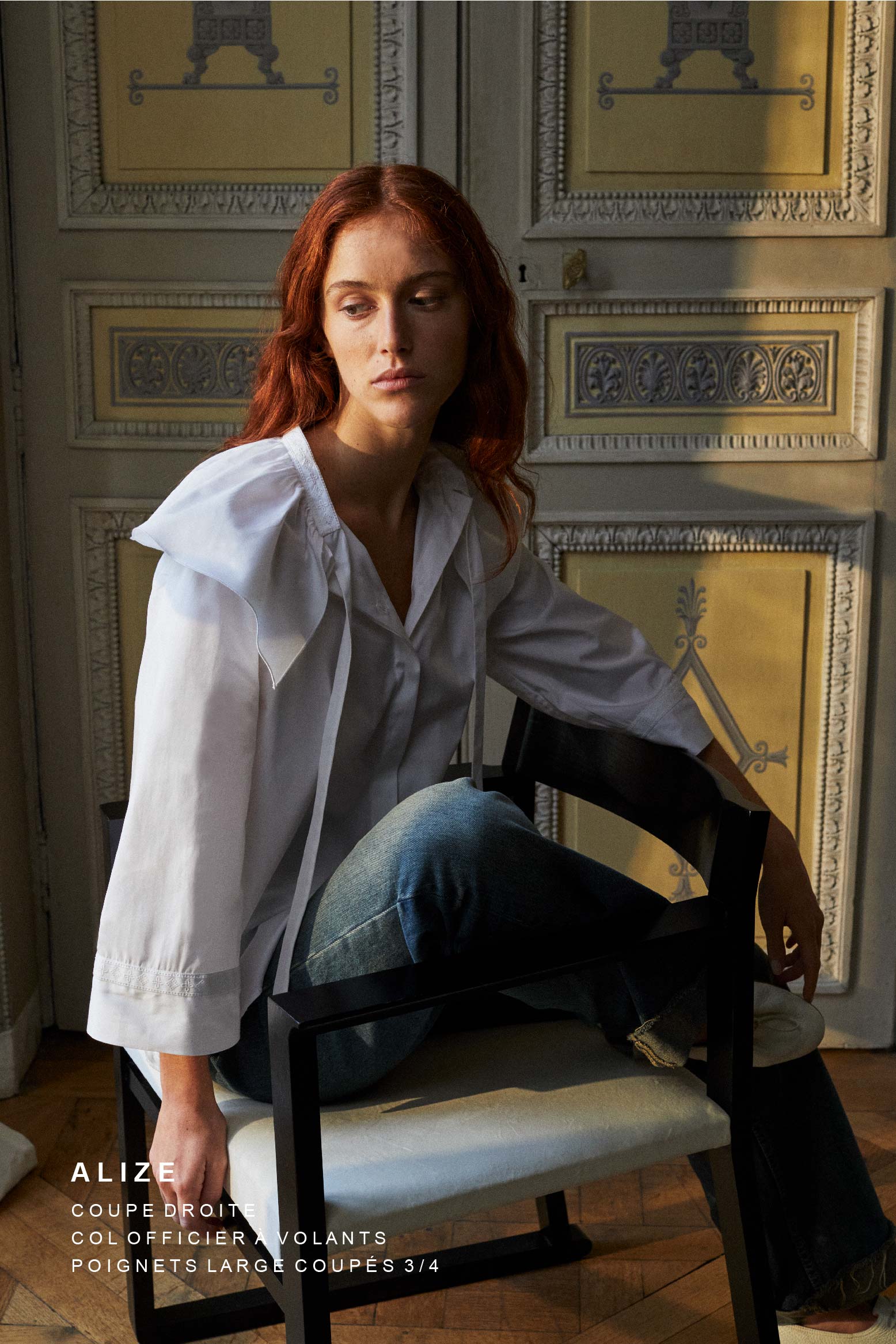 Mannequin rousse, assise sur une chaise, portant la chemise Alizé de Bourrienne Paris X avec un col brodé et orné d'un volant assumé, des maches évasées coupées trois-quart également brodées sur les poignets.