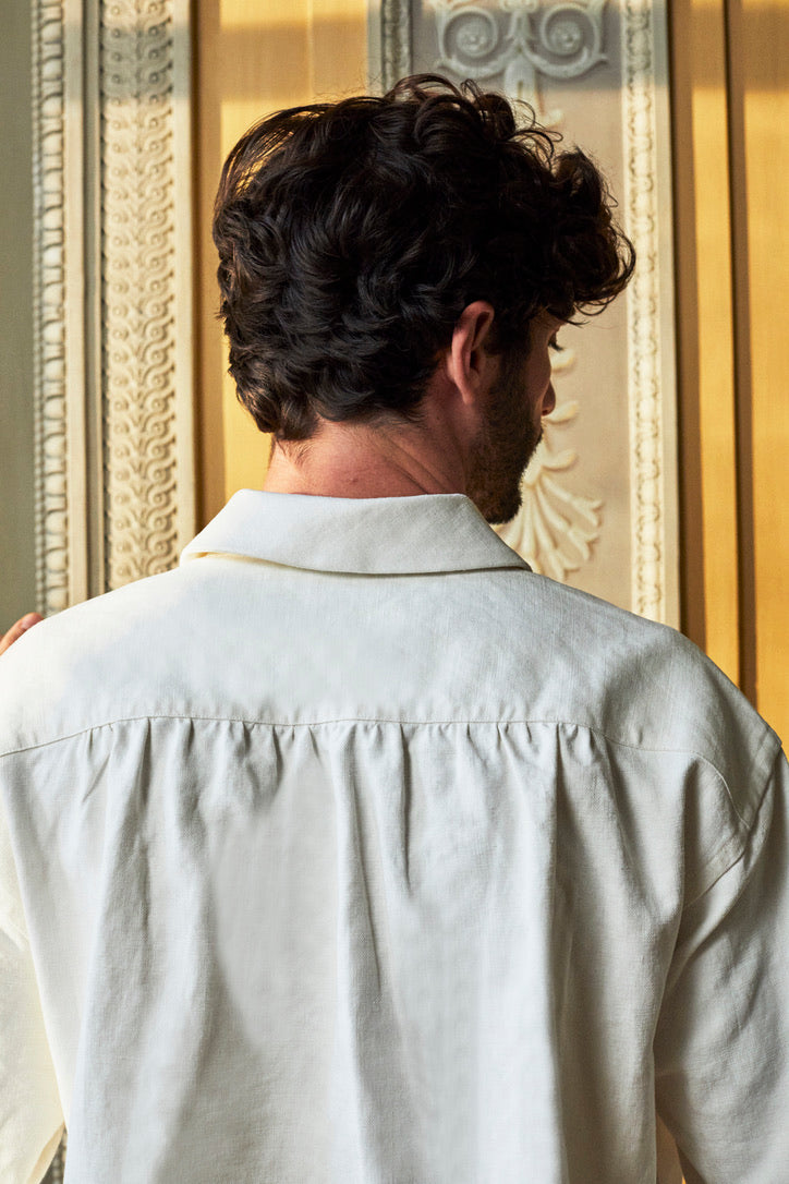 Vue sur le dos d'une chemise en lin blanc Bourrienne Paris X, portée par un homme brun,, soulignant les fronces délicates dans le dos.