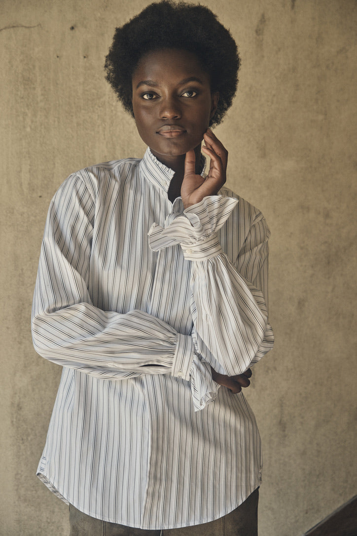 Plan américain d'une femme portant la chemise BOUDOIR Rayée Kaki, avec ses poignets à volants.