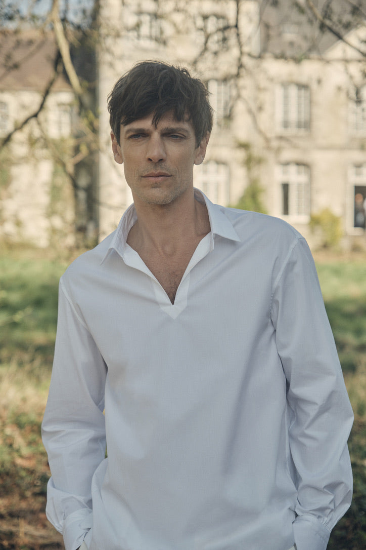 Photo plan taille d'un homme portant une chemise qui se nomme VOYAGE, elle est en 100% Coton, fabriqué en Europe, une coupe Bourrienne, un col Français et des poignets Bourrienne. Ses deux mains sont rentrées dans ses poches de pantalons. 