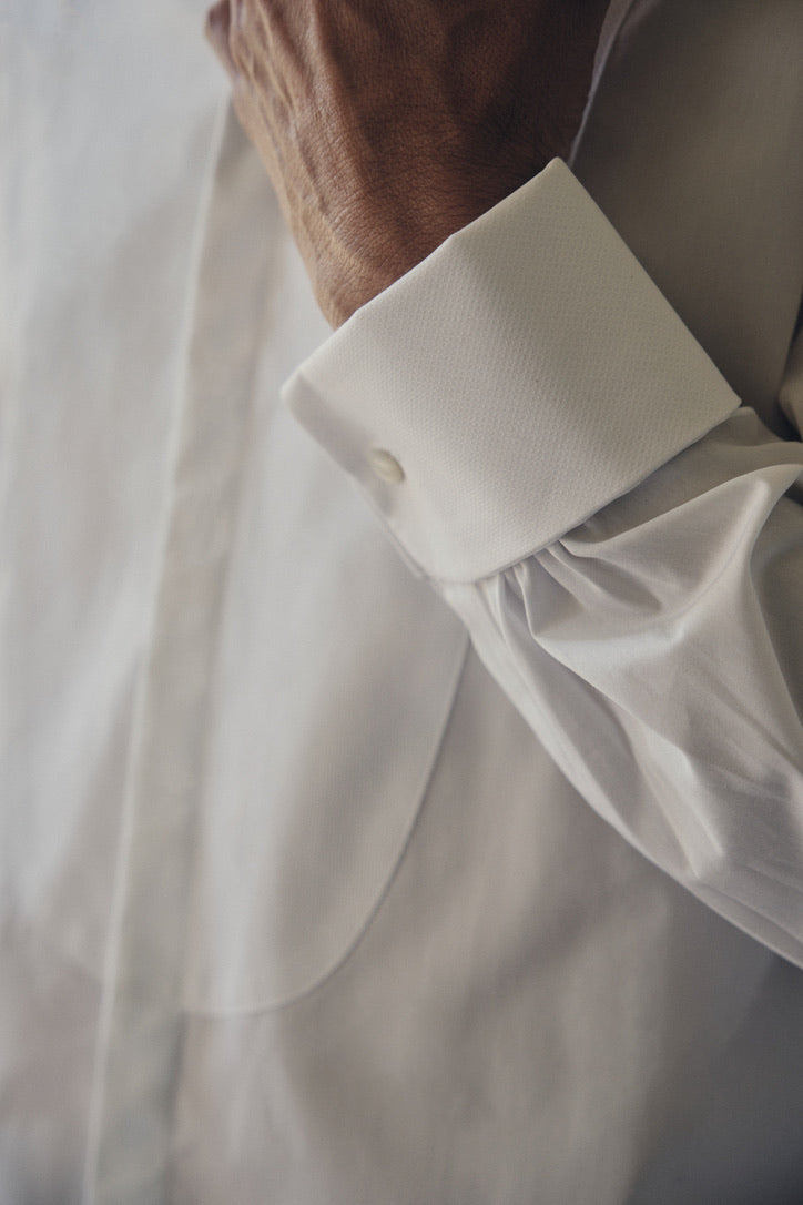 Photo gros plan d'un buste d'homme montrant le detail d'une chemise blanche, son poignets Français, une chemise à la coupe Bourrienne, un col haut officier avec un plastron. 