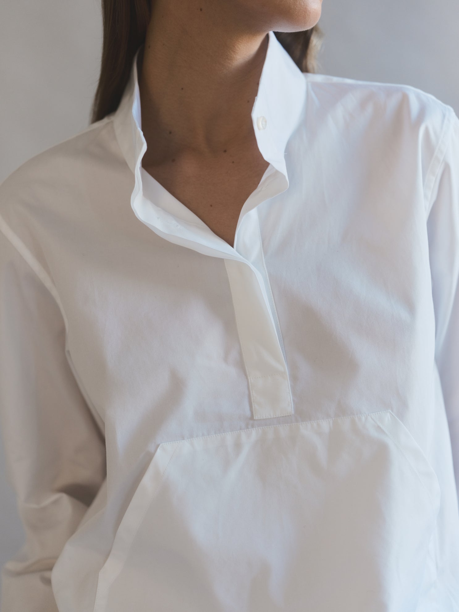 La chemise ALTITUDE, version sportswear de la chemise blanche, allie praticité et élégance. Son col haut, sa poche avant et son cordon de serrage en bas ajoutent une touche de style décontracté à votre tenue.