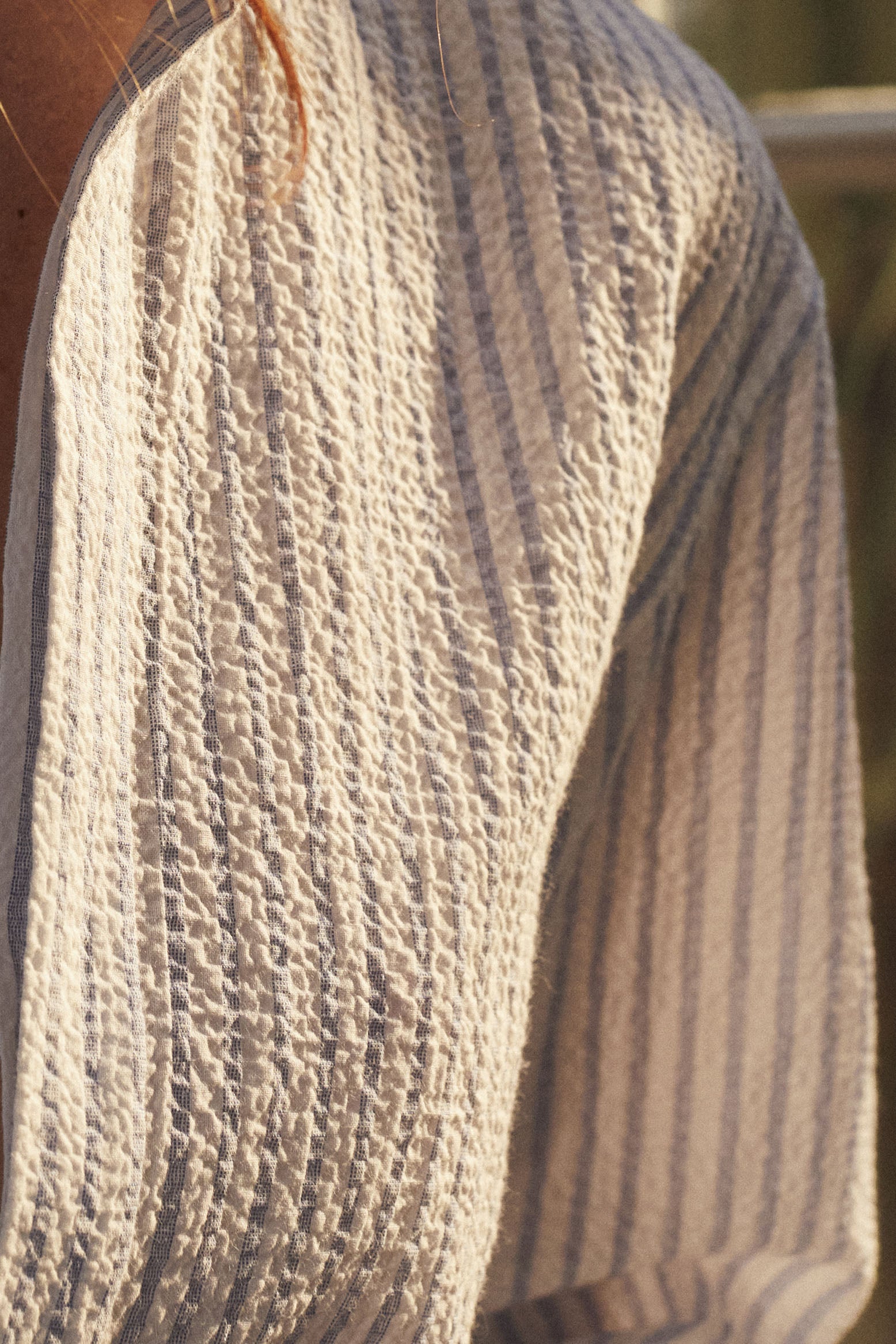 Close-up sur le tissu gaufré de la chemise AMAZONE Seersucker rayée bleu et blanc.