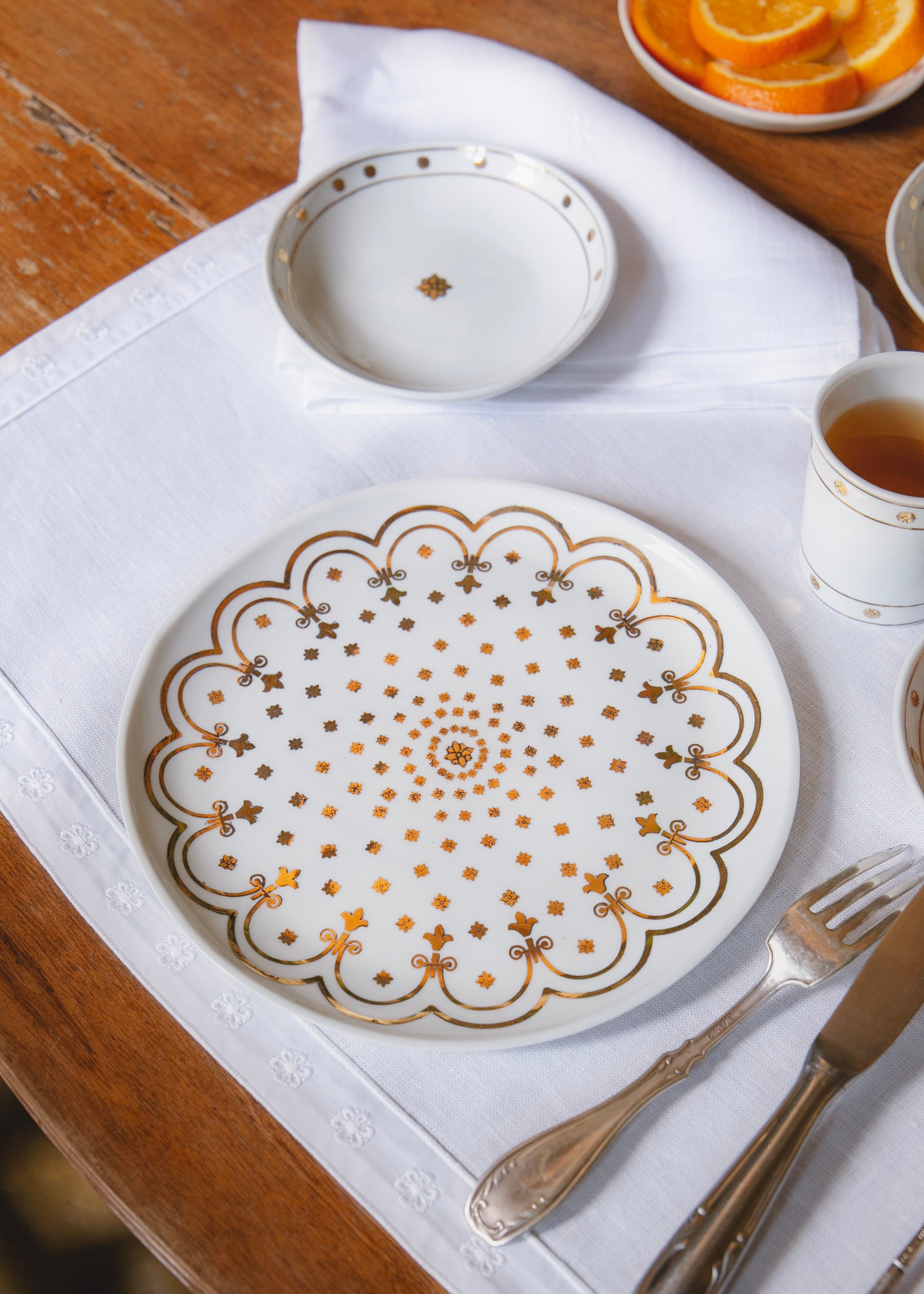 Assiette en porcelaine issue de la collaboration Bourrienne Paris X et Alix D. Reynis posée sur le set de table avec la coupelle et la timbale issues de la même collaboration